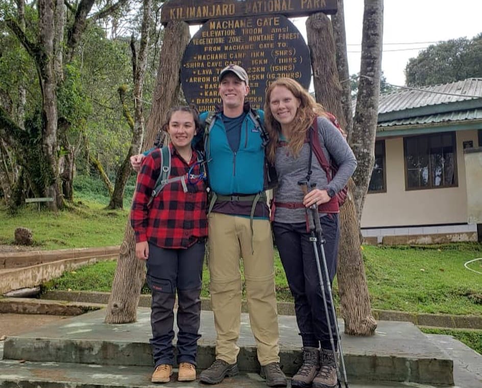 Family of three hiking the Machame Route on Mount Kilimanjaro, trekking through lush rainforest trails with scenic views in Tanzania