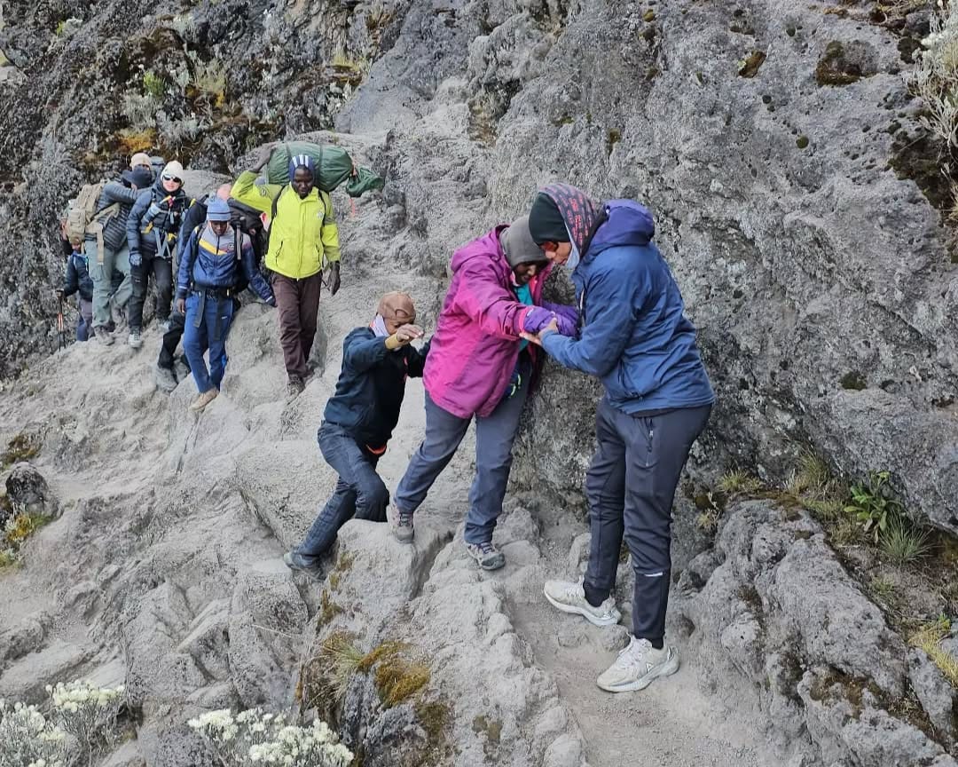 People at Jiwe la Kubusu on Mount Kilimanjaro enjoying scenic mountain views during a climbing adventure in Tanzania.