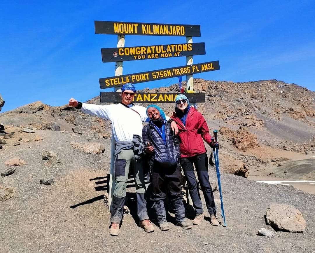 Climbers taking photos at Stella Point on Mount Kilimanjaro, celebrating their achievement near the summit during a trekking expedition in Tanzania.