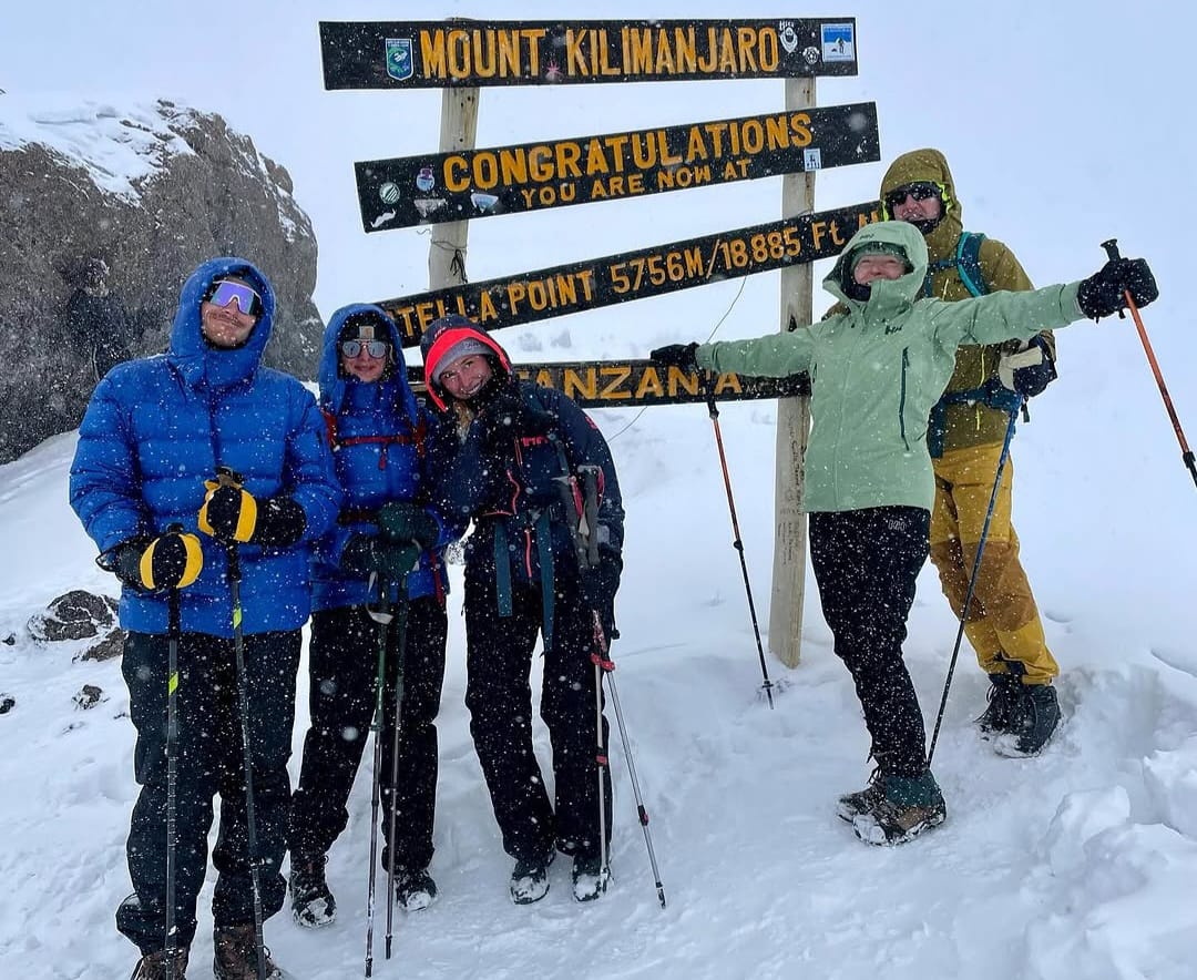 Climbers taking photos at Stella Point on Mount Kilimanjaro, celebrating near the summit with stunning high altitude views in Tanzania
