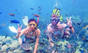 Tourists snorkeling in clear turquoise waters over colorful coral reefs in Zanzibar