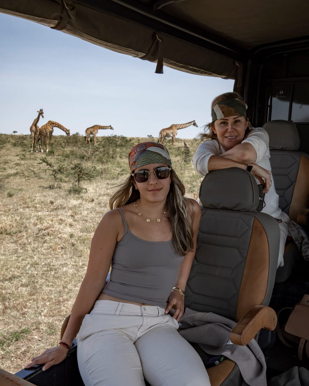 Tourist taking photos of a giraffe during a Kenya safari in Masai Mara National Reserve