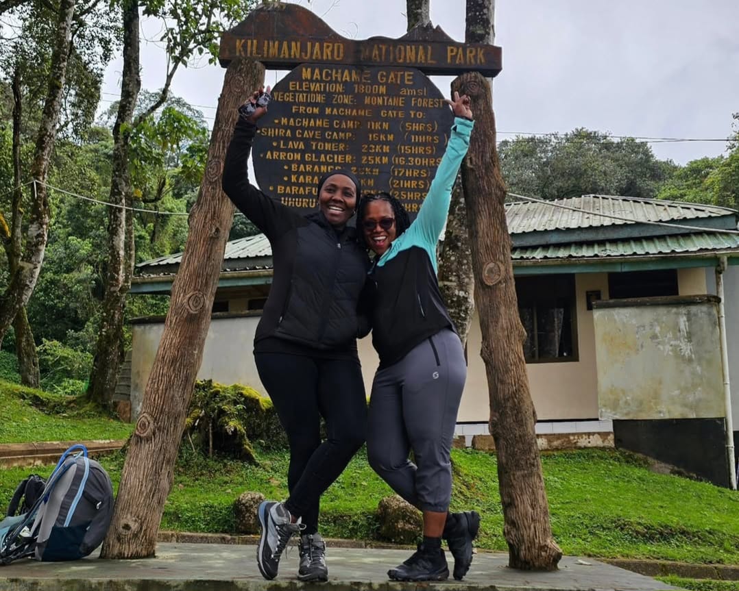 Two women trekking the Machame Route on Mount Kilimanjaro, hiking through scenic trails with backpacks and mountain gear in Tanzania